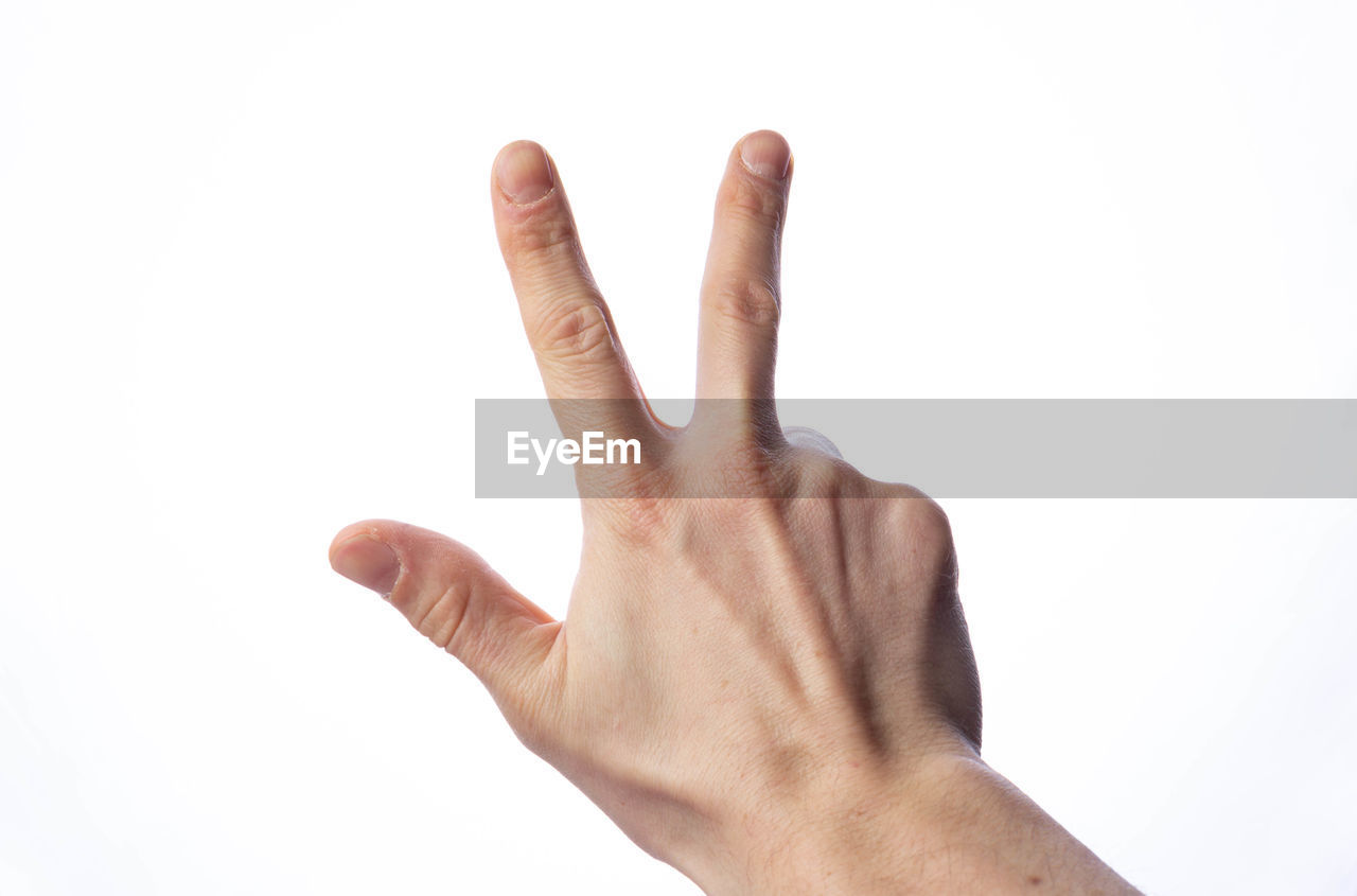 CLOSE-UP OF HUMAN HAND OVER WHITE BACKGROUND