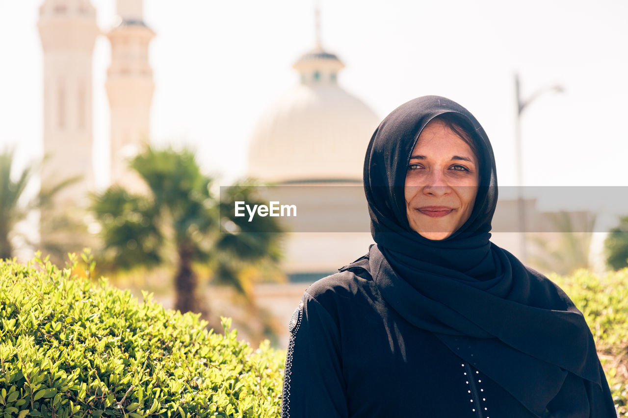 Portrait of woman wearing traditional clothing while standing against mosque