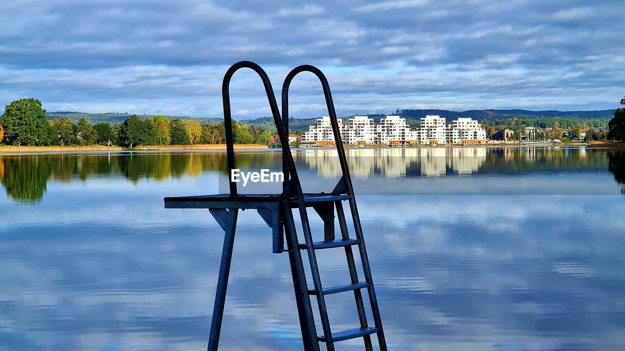 Metallic structure by river against sky in city