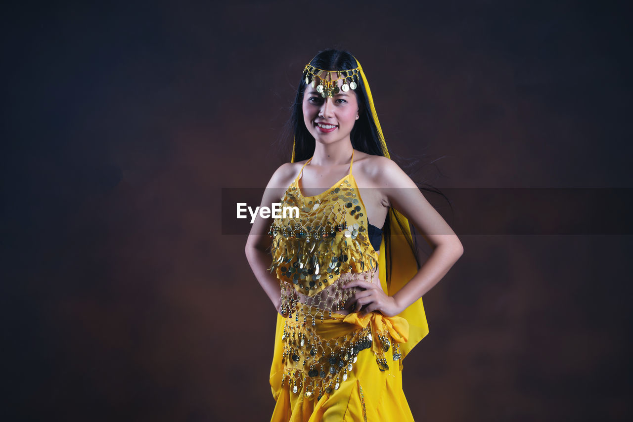 PORTRAIT OF A SMILING YOUNG WOMAN AGAINST YELLOW