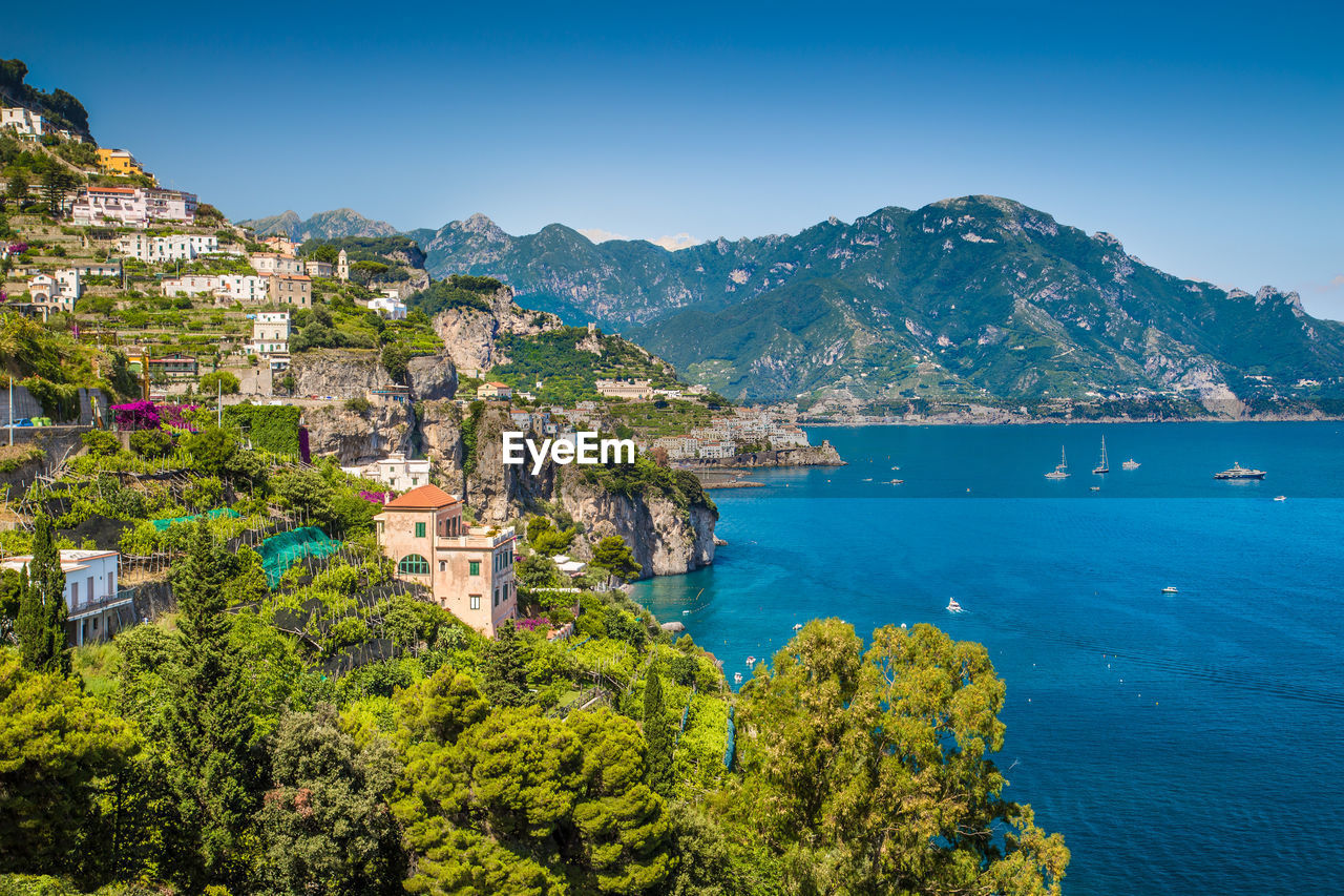 Scenic view of sea by townscape against sky