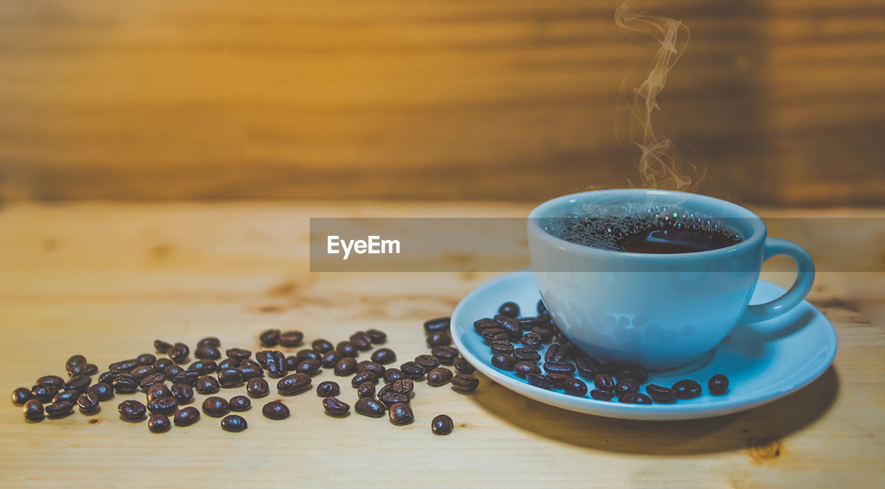 CLOSE-UP OF COFFEE CUP ON TABLE AGAINST WALL