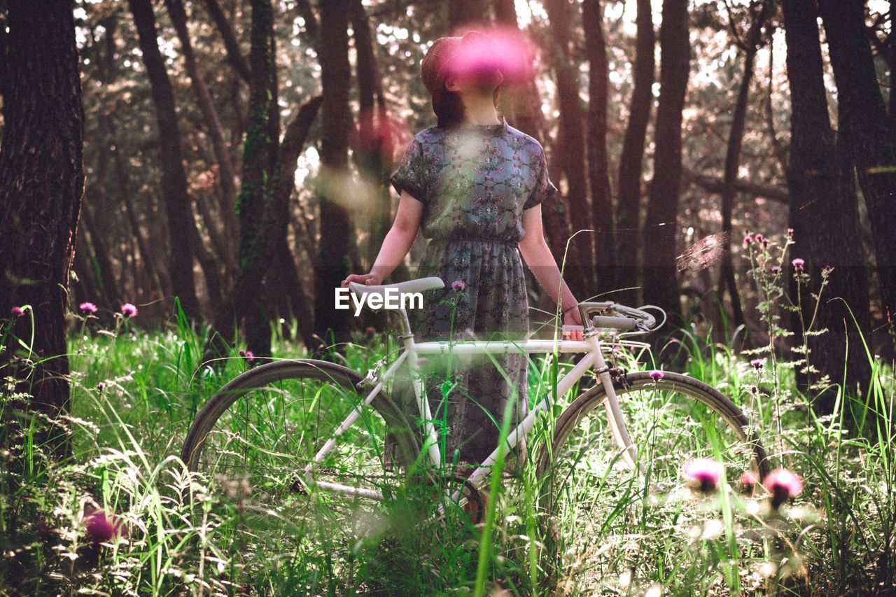 Woman with bicycle standing on grassy field