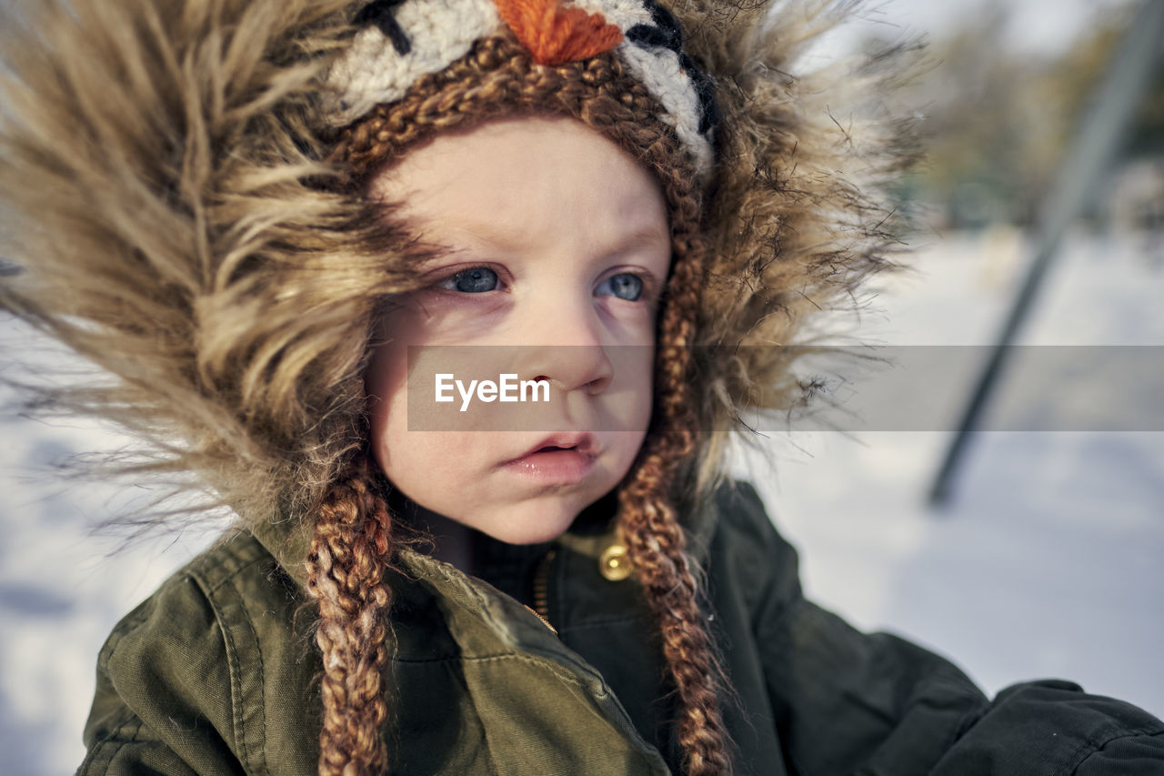 Close-up of cute girl in warm clothing on snow