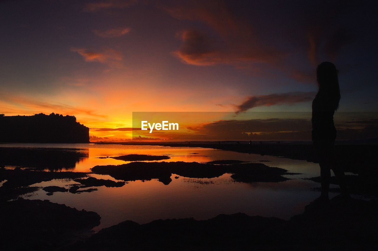 Scenic view of sea against cloudy sky at sunset