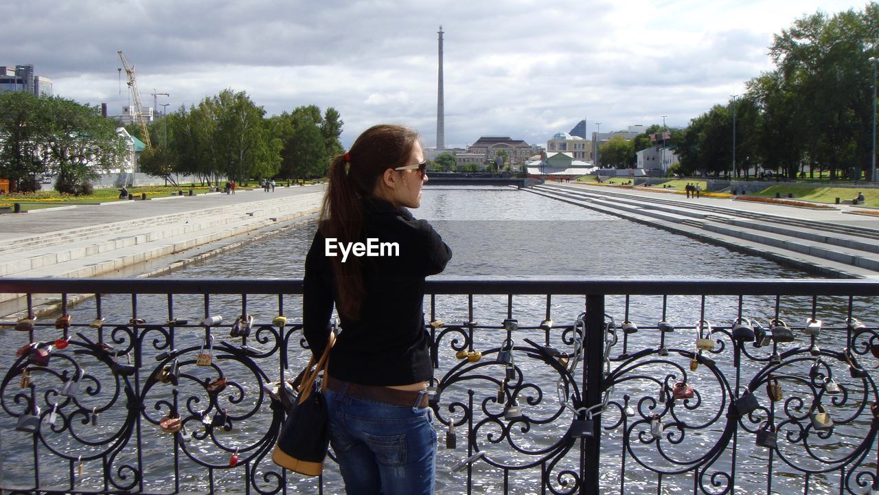 Rear view of woman standing on bridge over canal against yekaterinburg tv tower