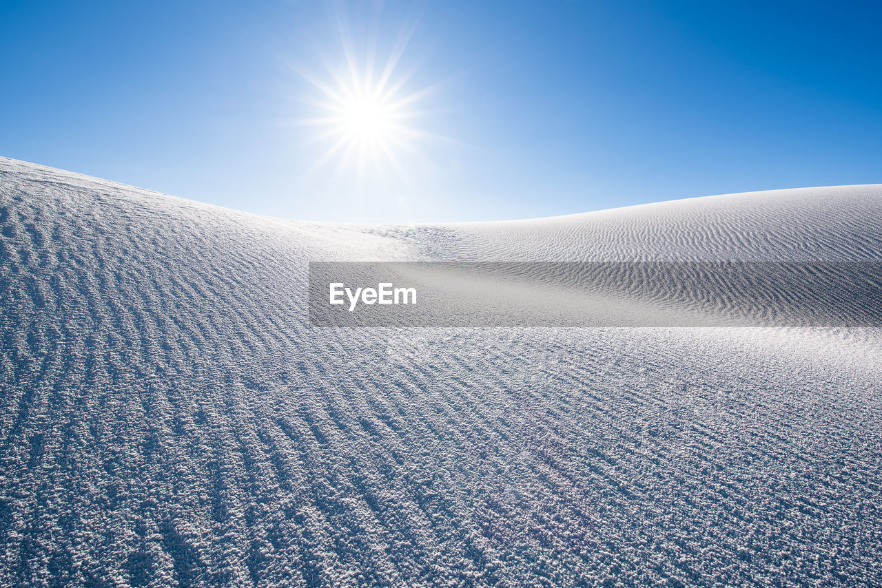 Scenic view of snowcapped landscape against sky on sunny day