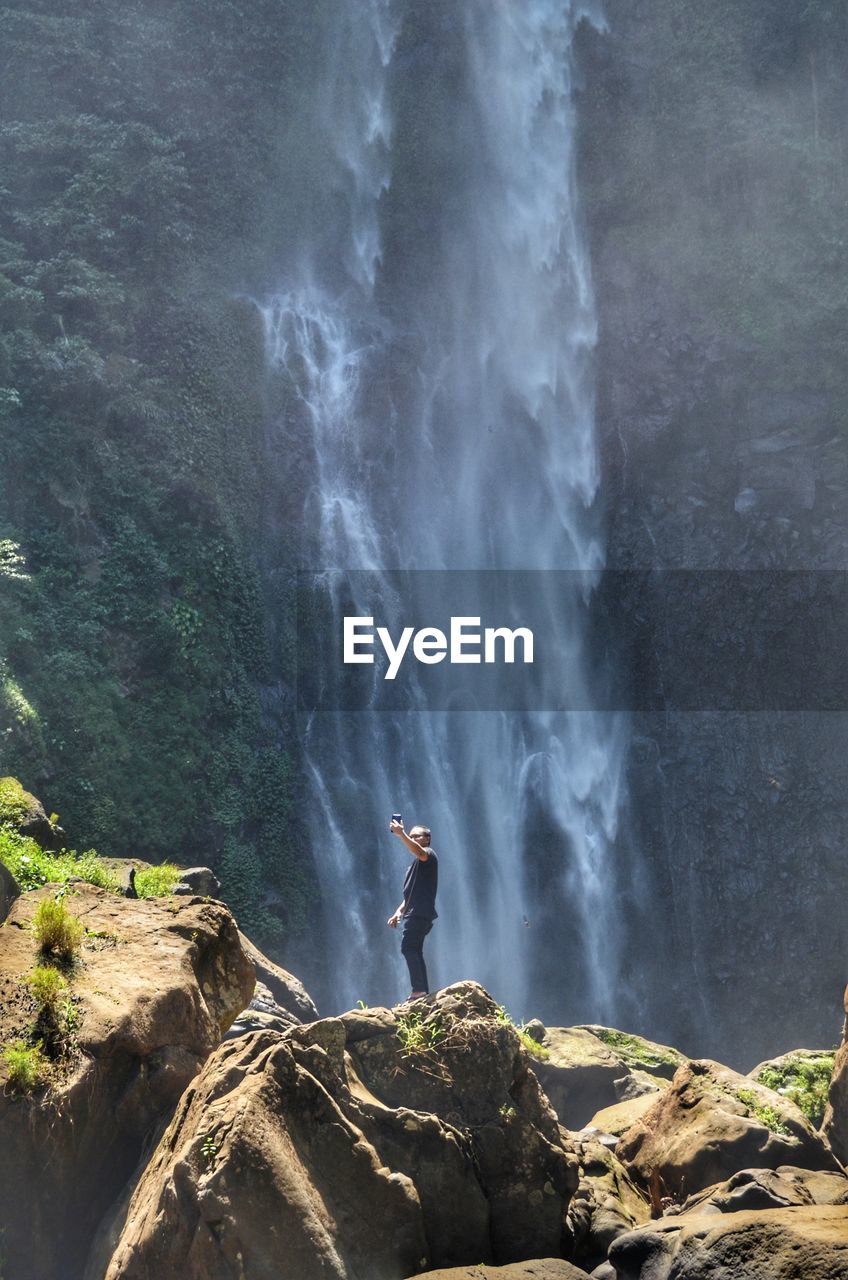 Man taking selfie against waterfall