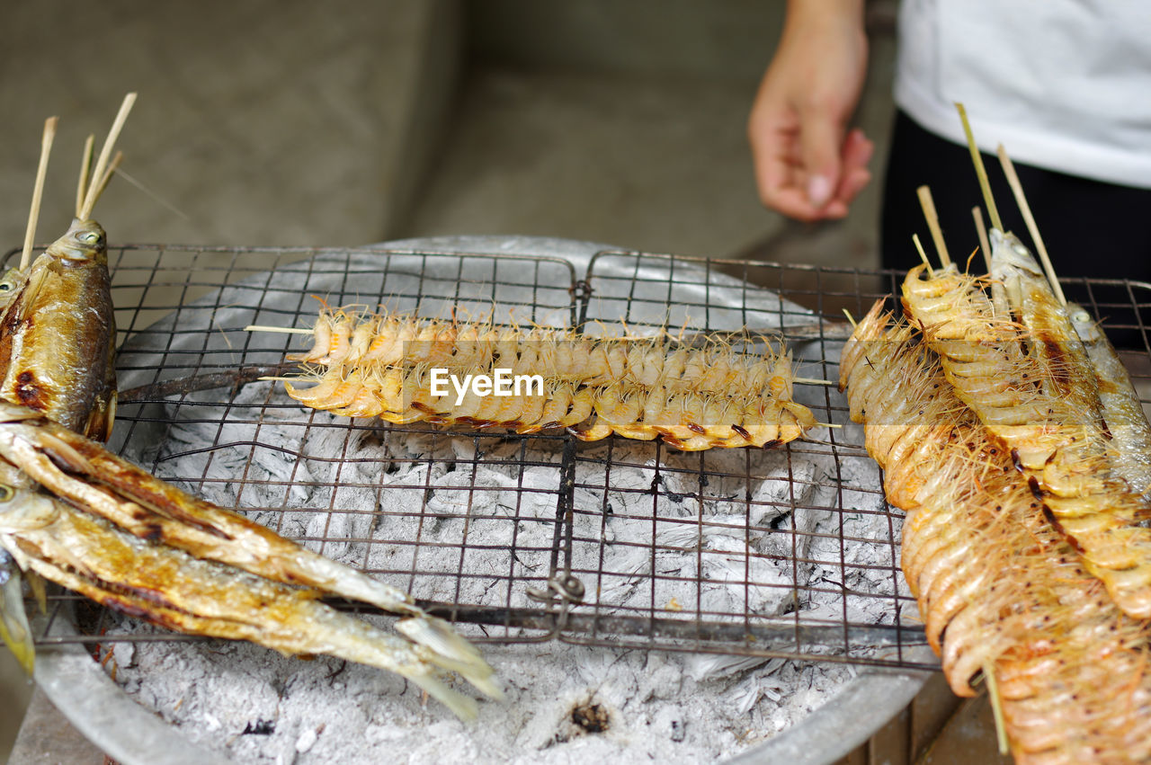 Close-up of person preparing food on barbecue grill