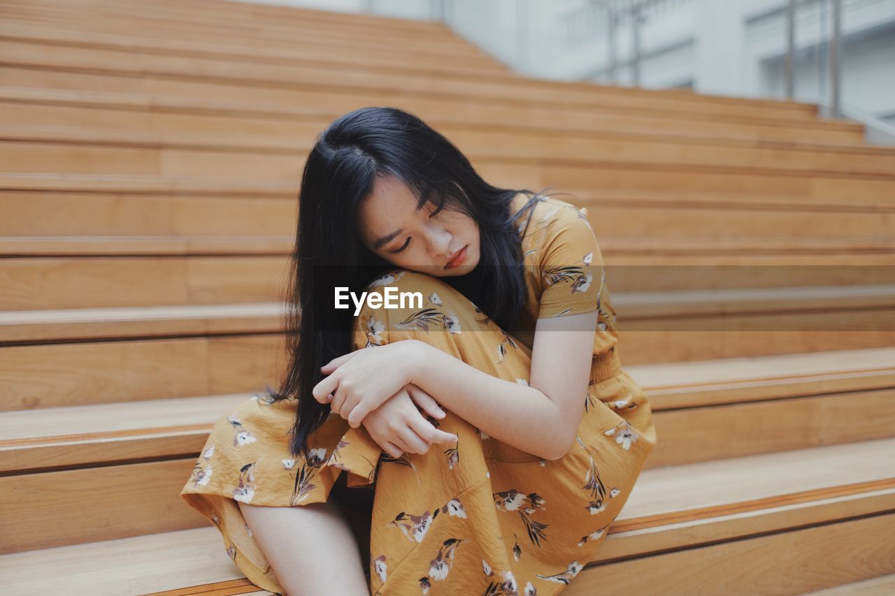 Sad young woman sitting on staircase