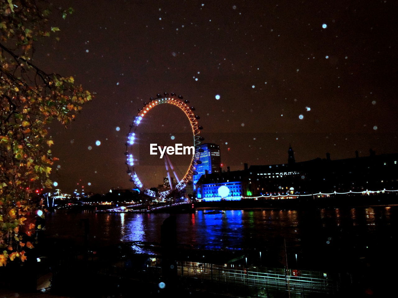 ILLUMINATED FERRIS WHEEL IN RIVER AT NIGHT