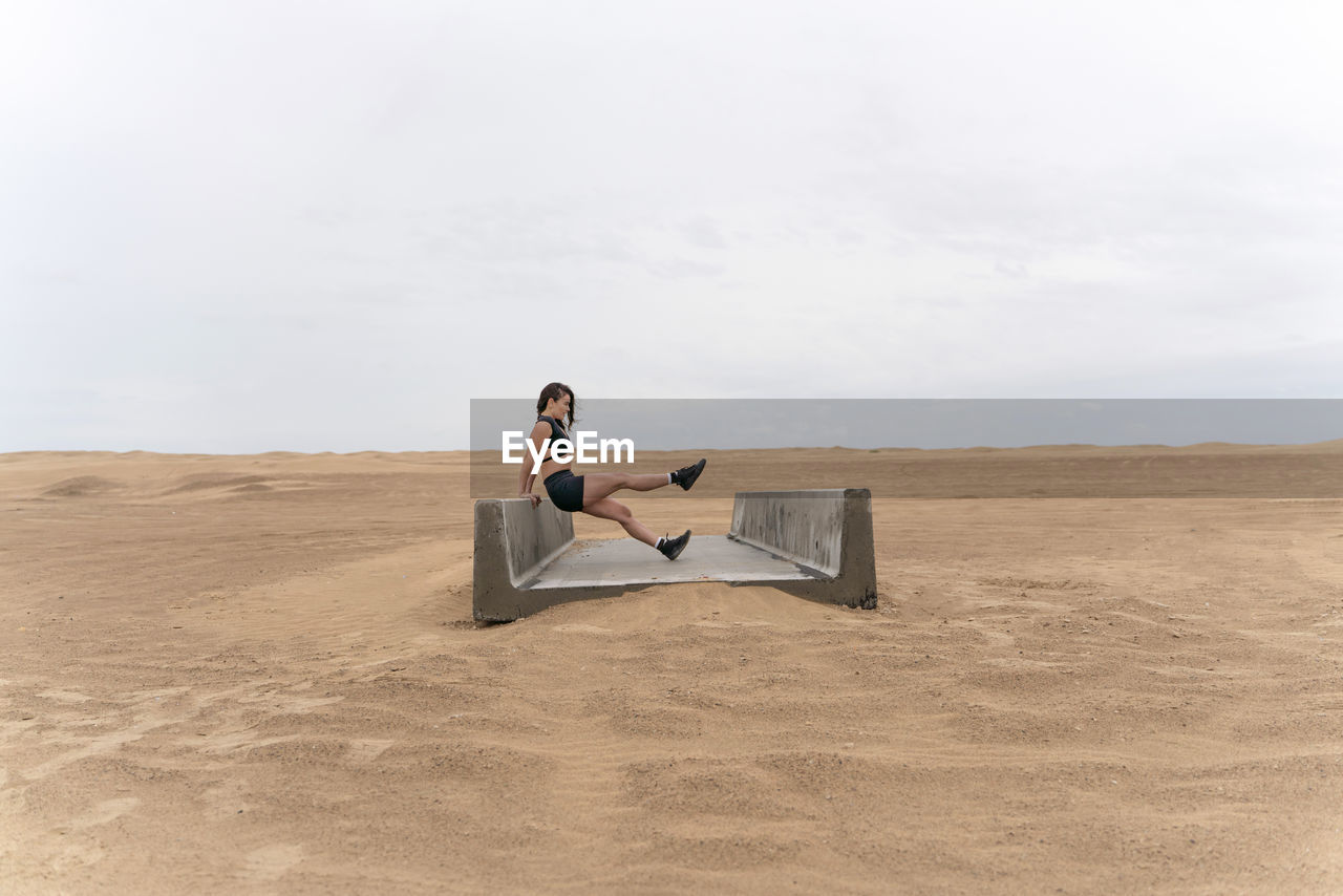 Woman exercising on concrete structure in desert