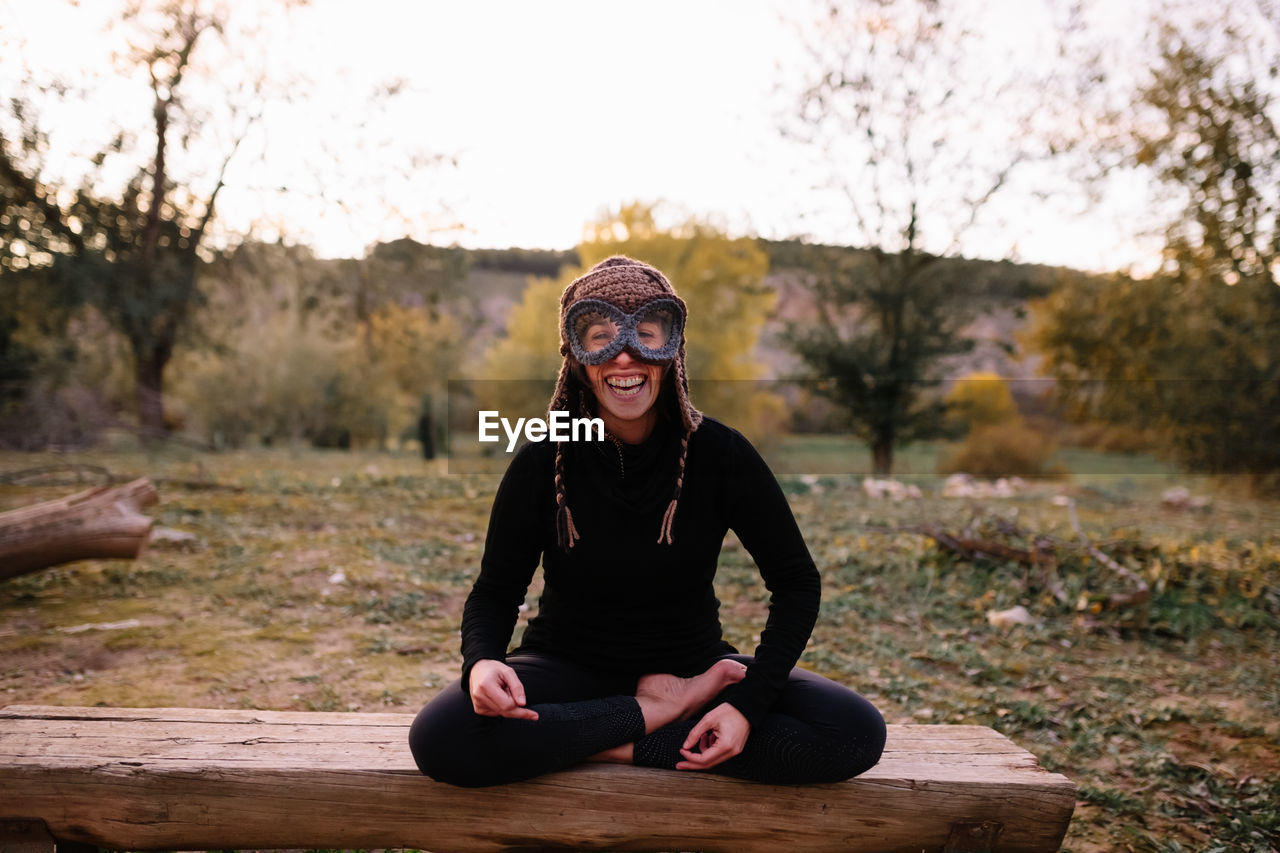 Portrait of smiling woman wearing knit hat sitting on bench at park