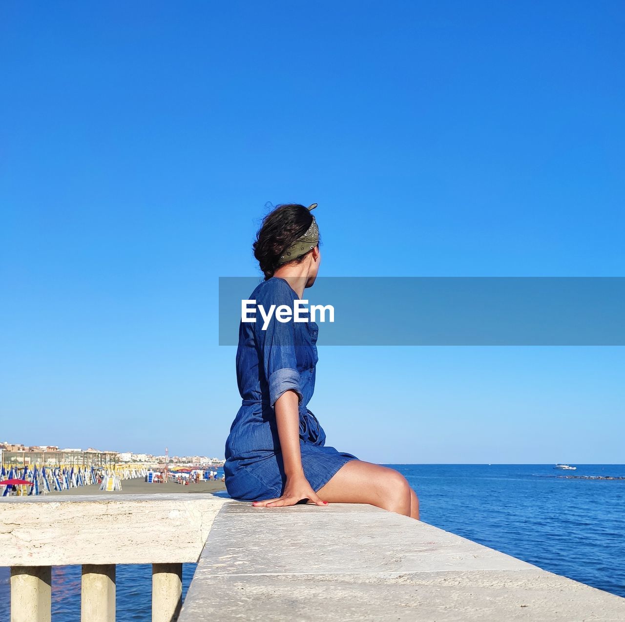 Woman looking at the beach against clear blue sky