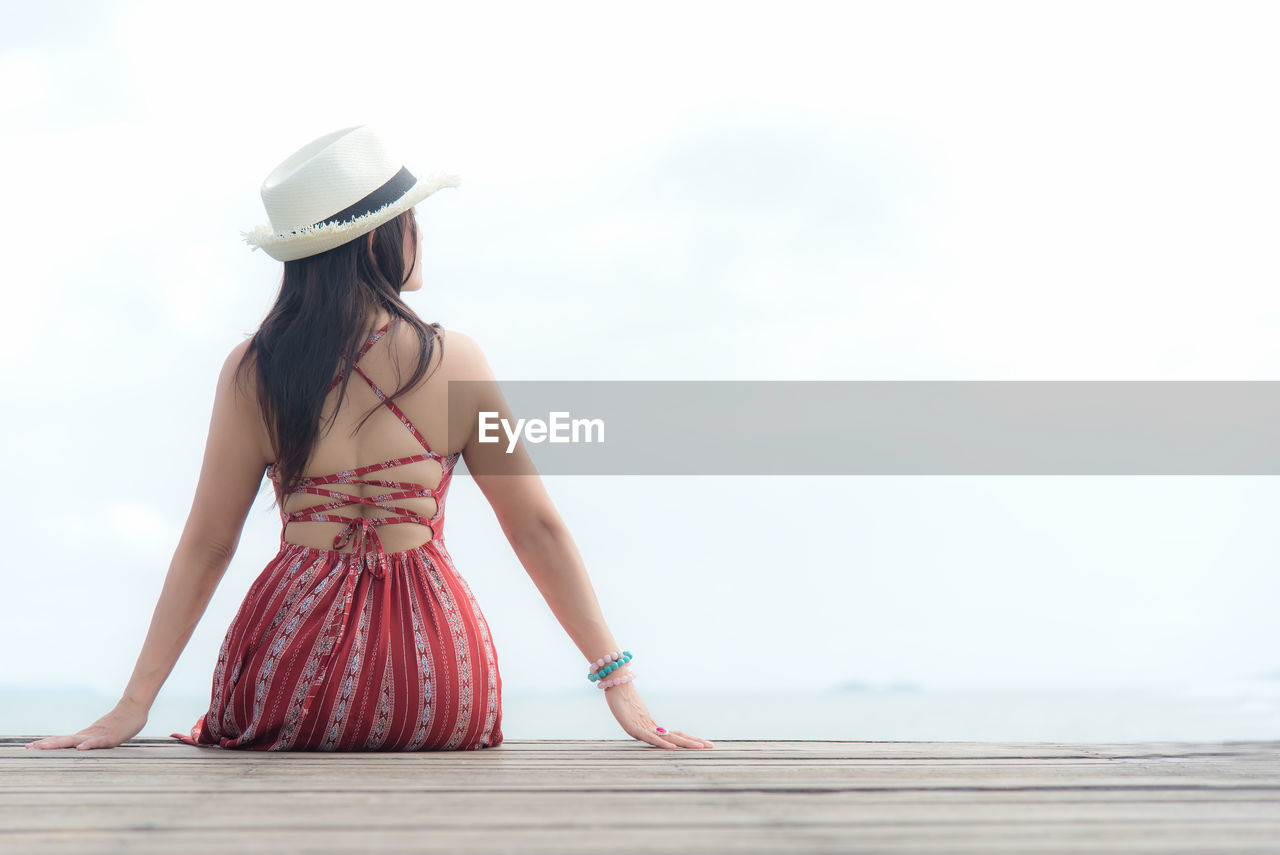 REAR VIEW OF WOMAN IN HAT AGAINST SKY