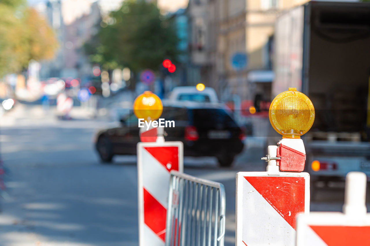 CLOSE-UP OF ROAD SIGN ON STREET AGAINST CITY