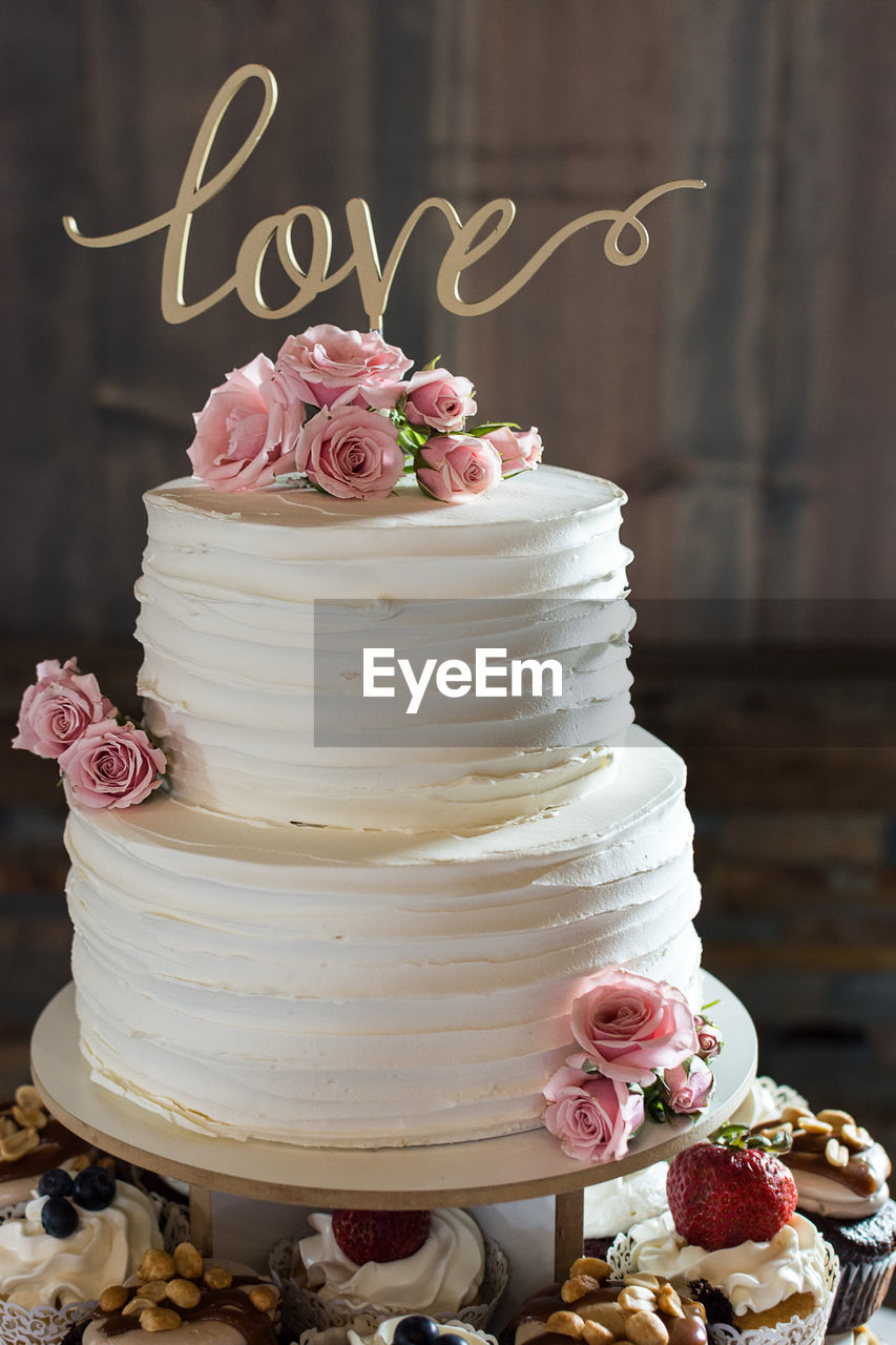 Rustic ruffled wedding cake with love topper and fresh pink roses