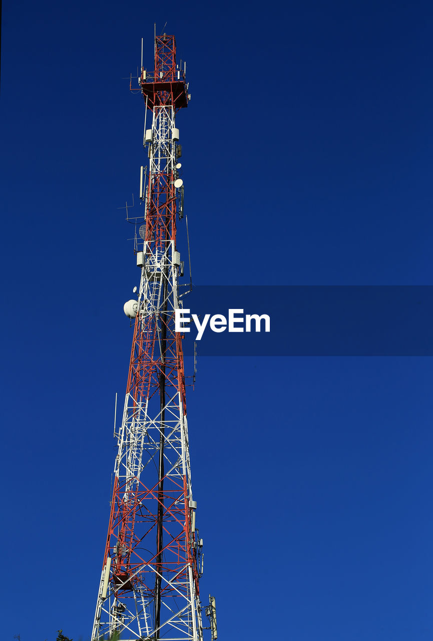 Low angle view of communications tower against blue sky