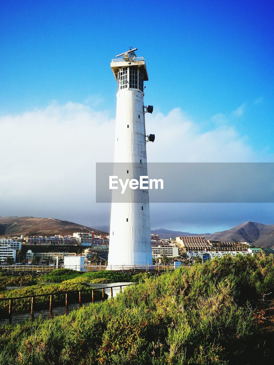 Lighthouse on landscape against sky