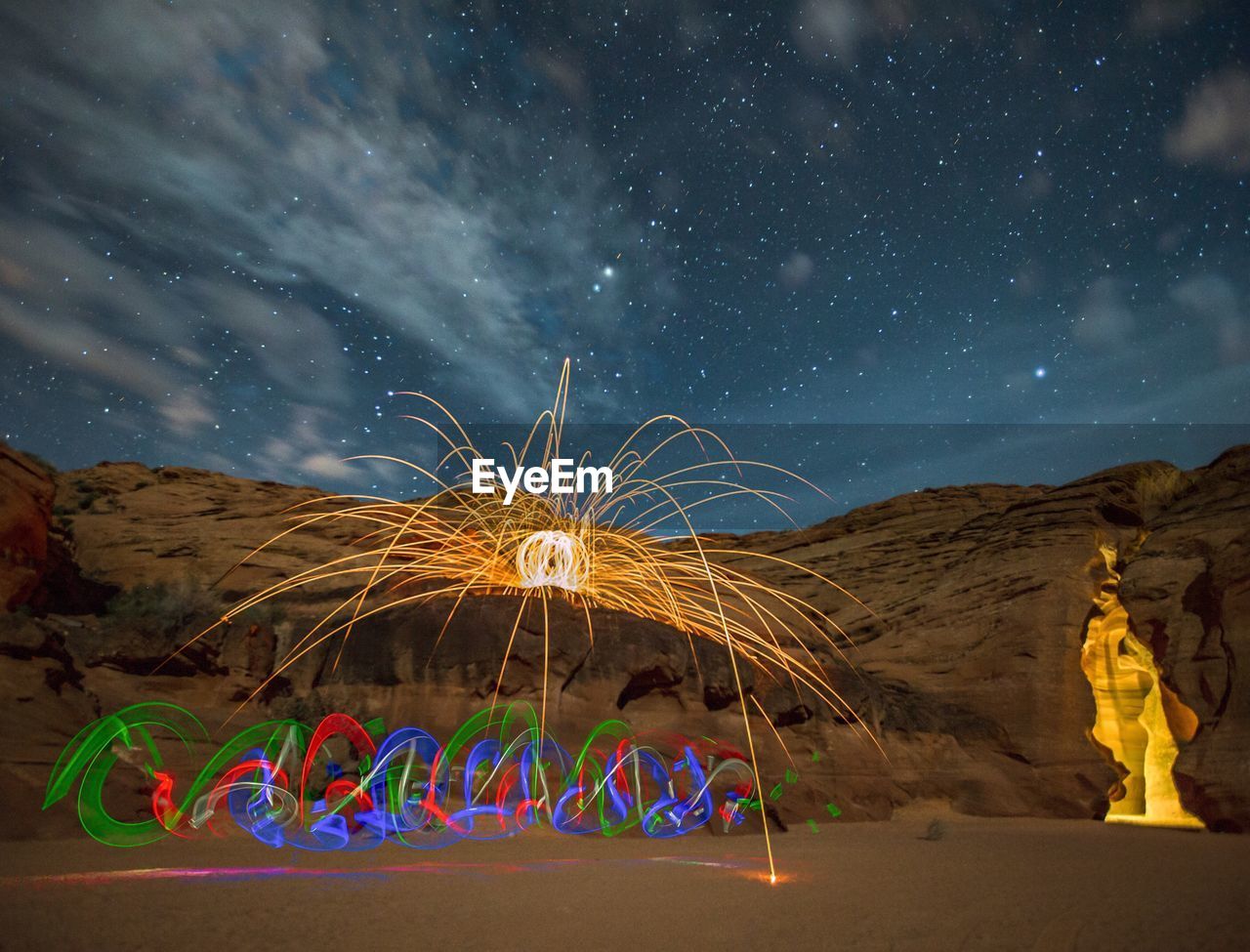 Light paintings by rock formations against star field at night