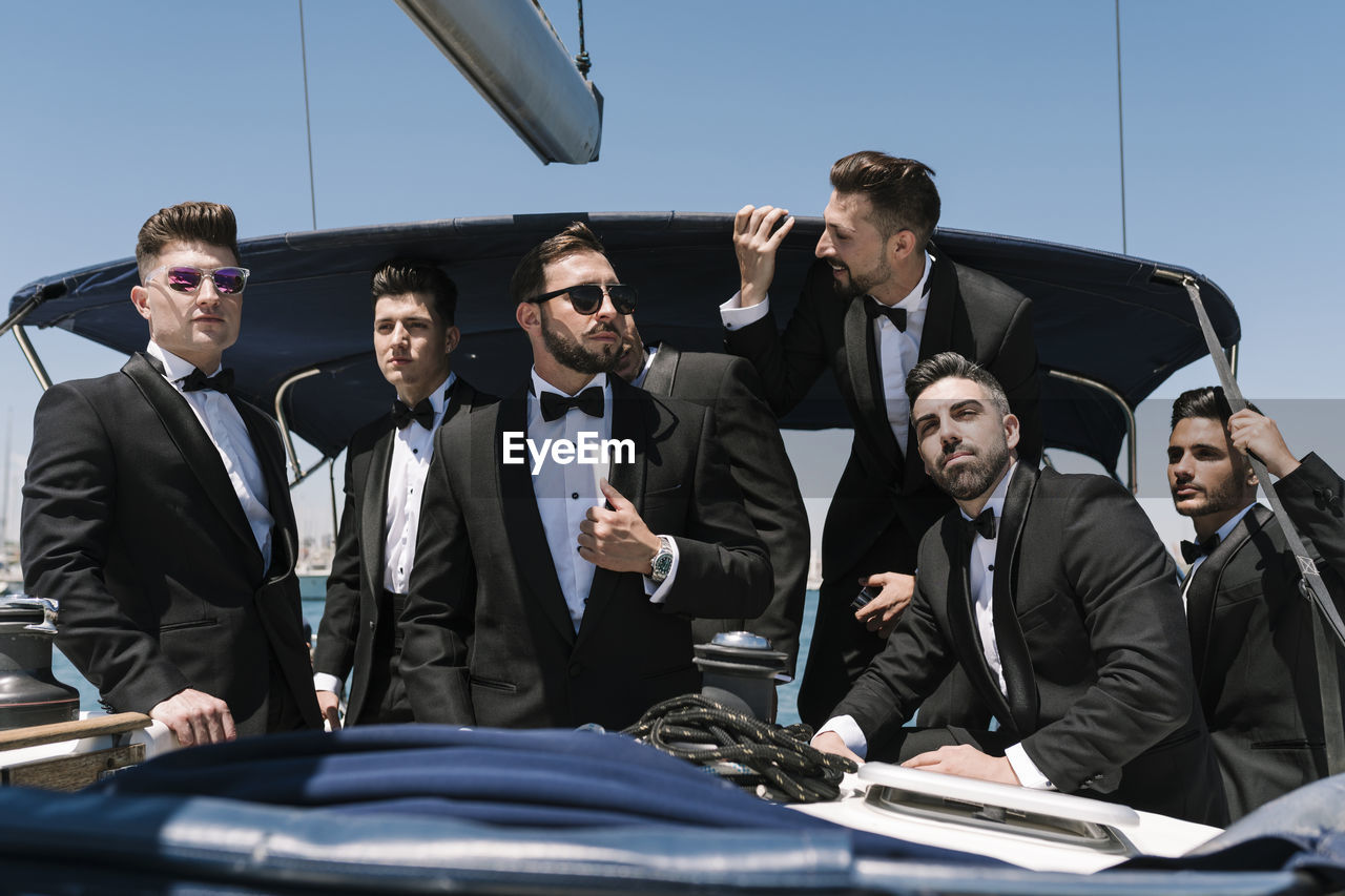 Elegant men looking away on yacht during summer