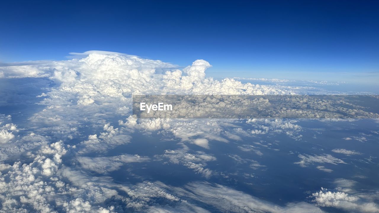 sky, mountain range, cloud, environment, mountain, aerial view, blue, nature, snow, scenics - nature, horizon, beauty in nature, cold temperature, winter, landscape, aerial photography, no people, outdoors, travel, white, sunlight, earth, day, high up, airplane, cloudscape, snowcapped mountain, tranquility, atmosphere, planet earth, space, high angle view, air vehicle, copy space, tranquil scene