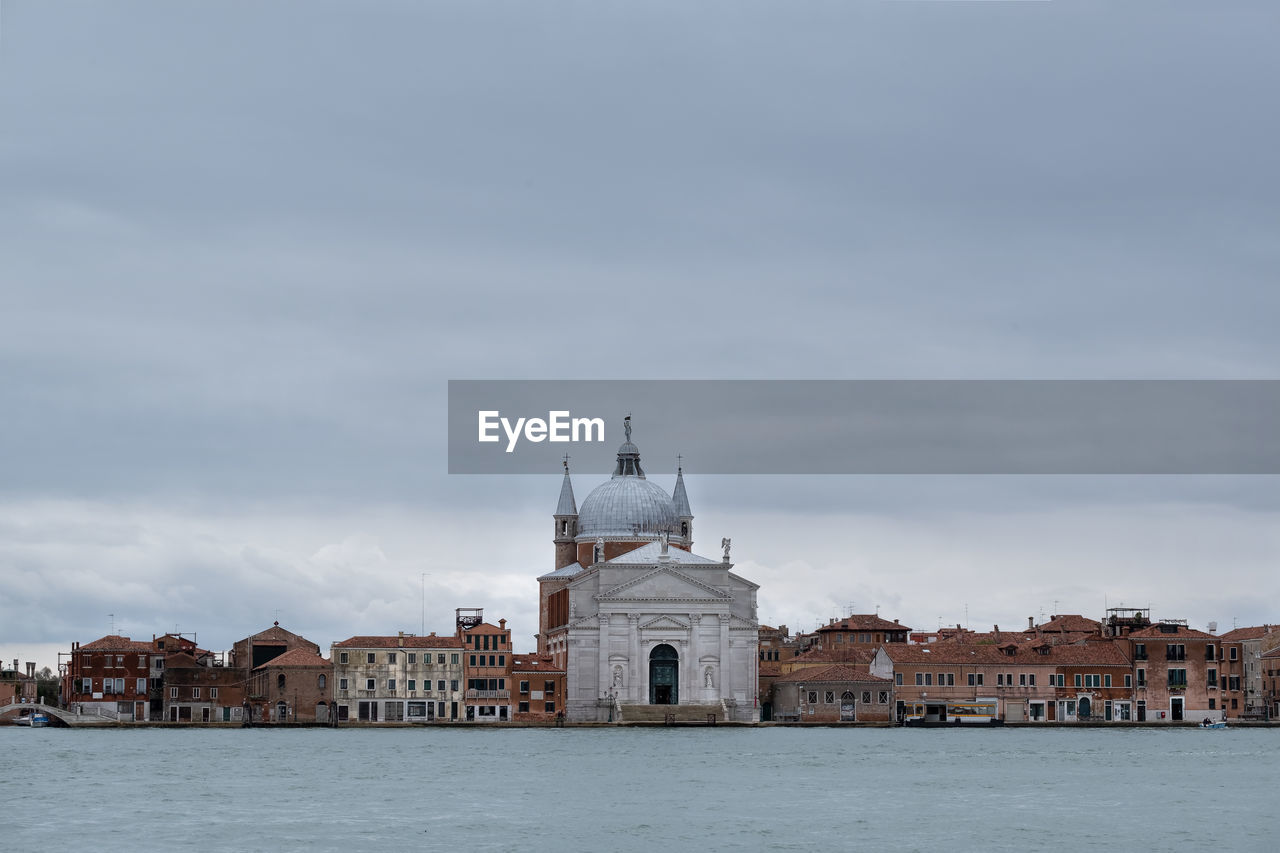 Buildings at waterfront in venice against cloudy sky