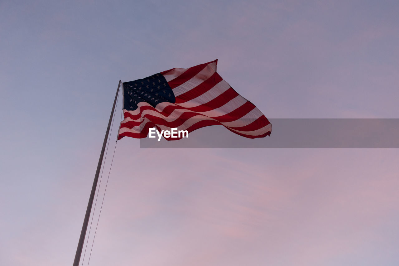 Low angle view of american flag waving against sky during sunset