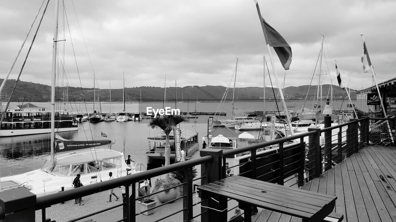 Sailboats moored at harbor against sky