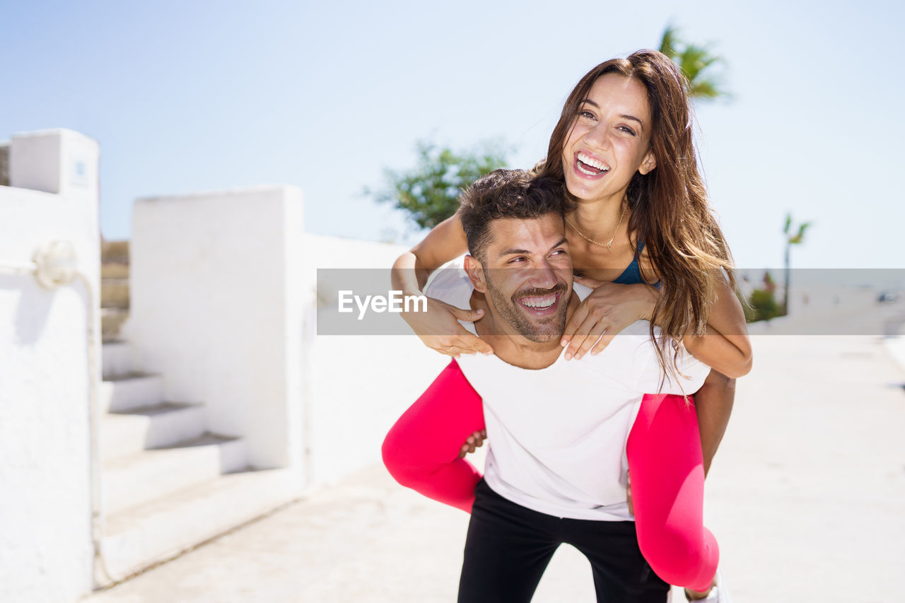 Smiling man carrying woman in back outdoors