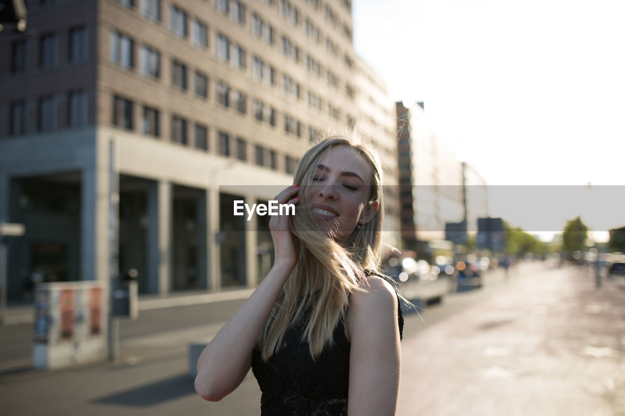 Smiling young woman standing on street in city