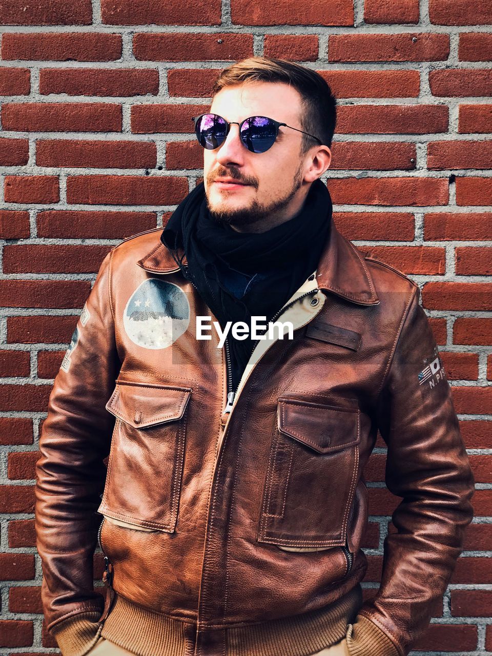 Handsome young man standing against brick wall