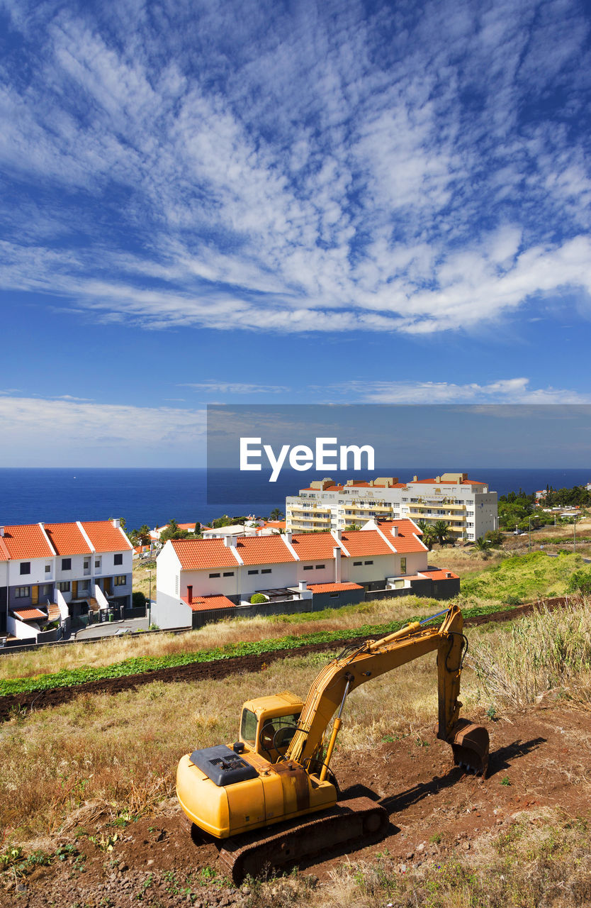 High angle view of buildings on mountain by sea against sky