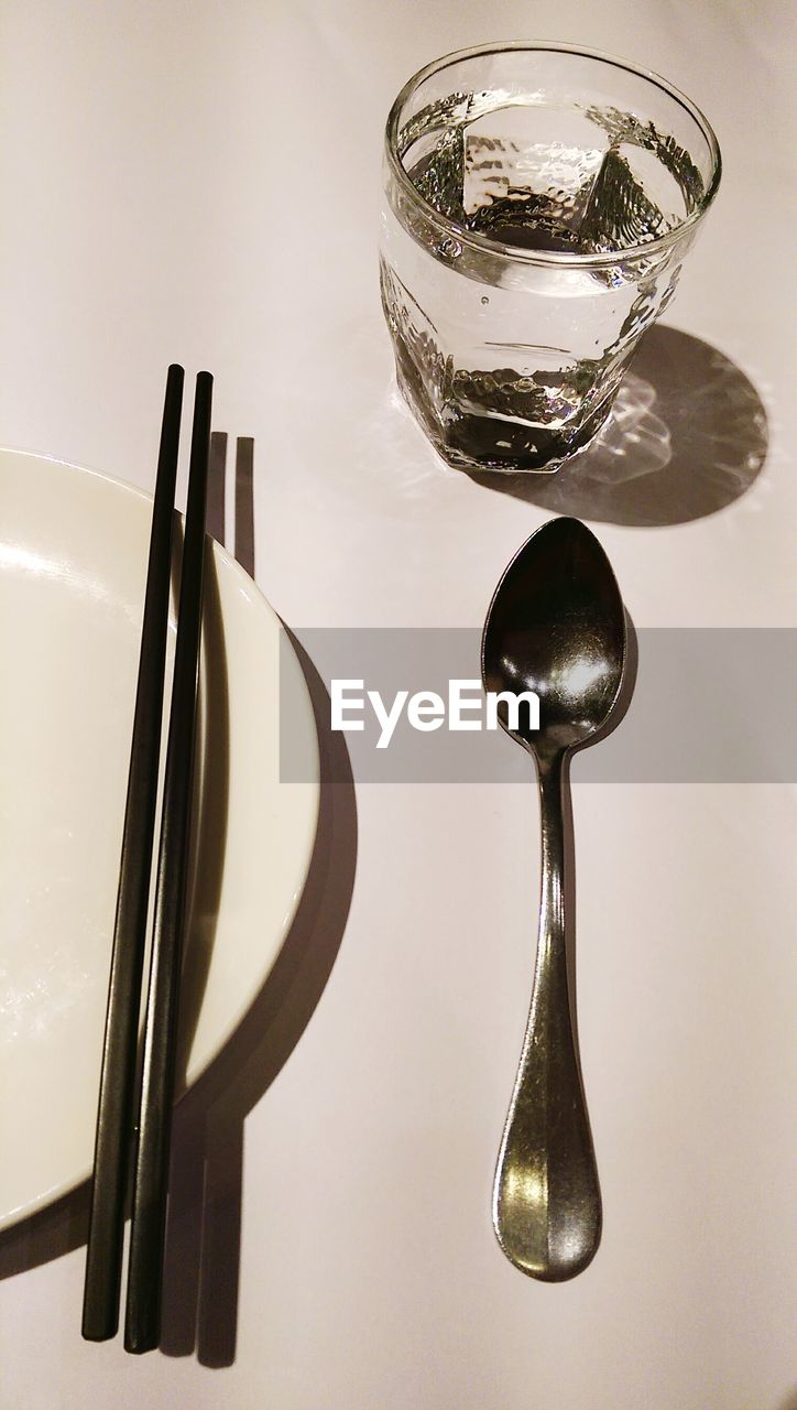 High angle view of drinking glass by plate and spoon on table
