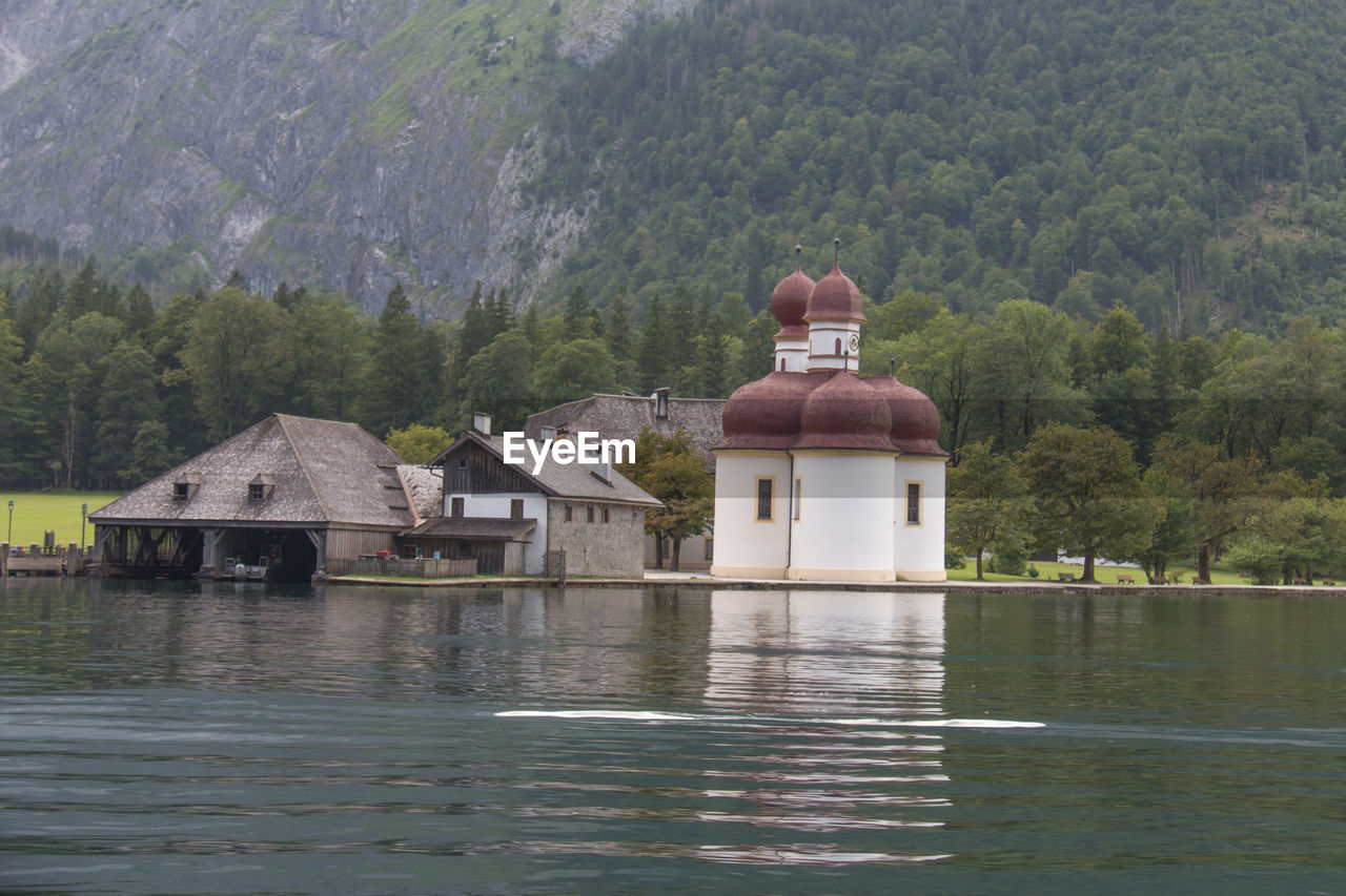 Built structure by lake against trees