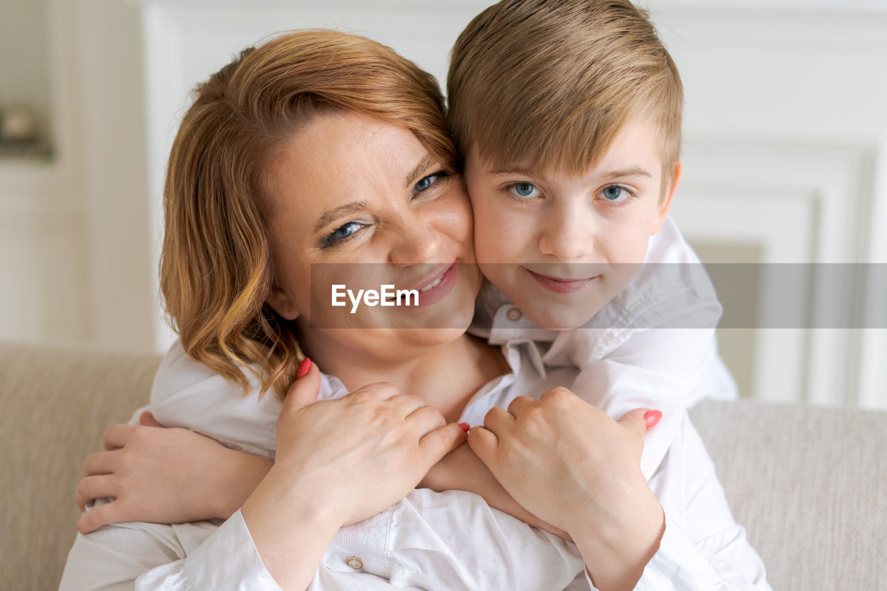 Head shot happy young woman hugging talking to little son having fun together