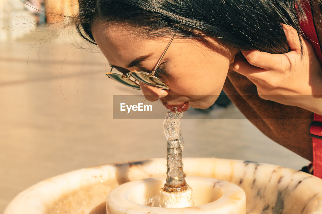 Asian tourist woman is drinking from public tap water.