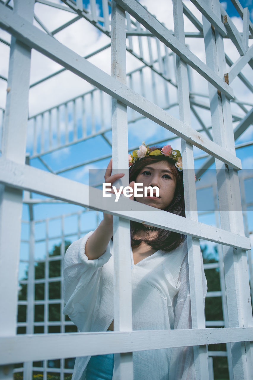 Portrait of woman standing by metallic built structure