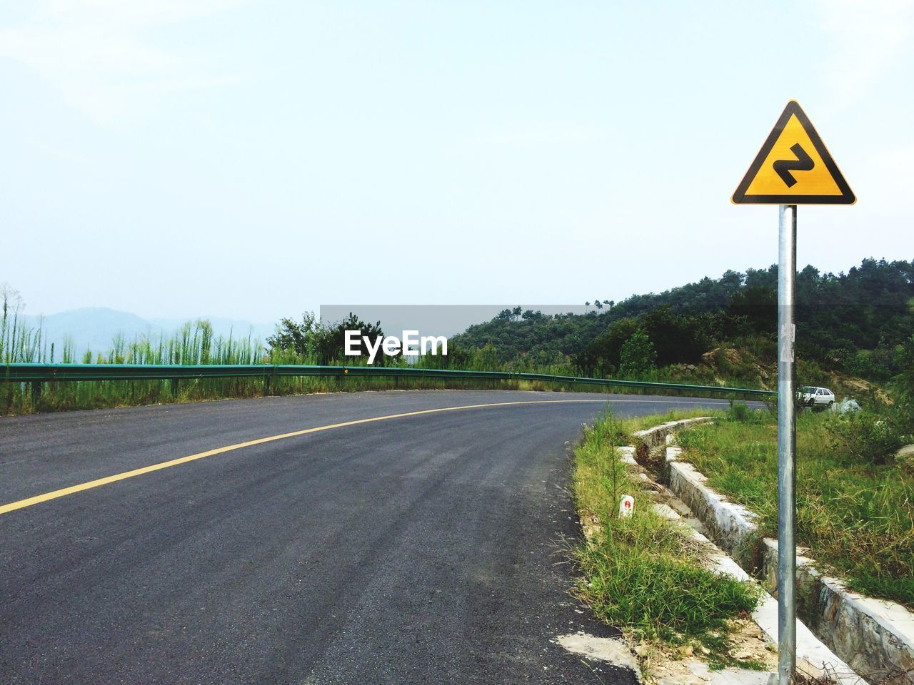 Road sign by street against sky