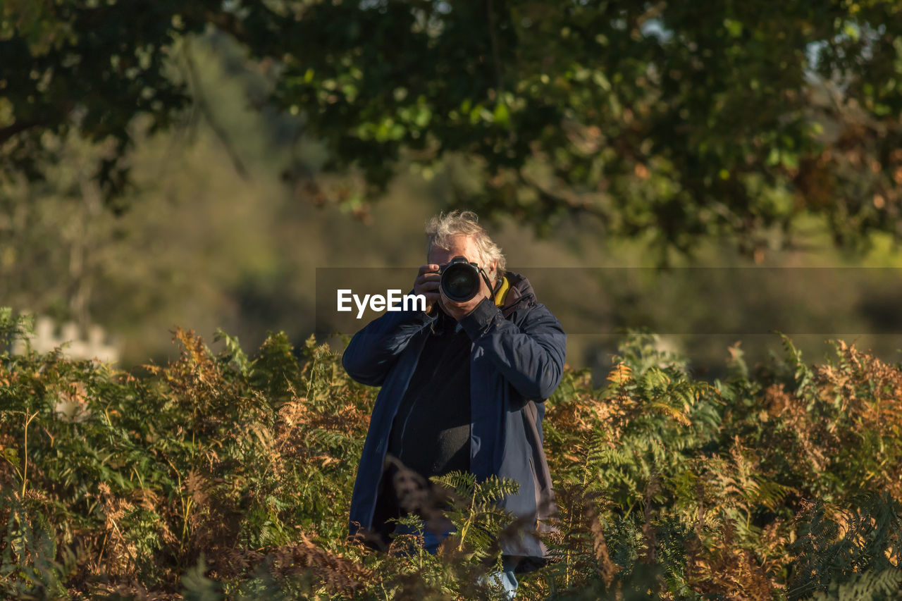 Senior man photographing against trees
