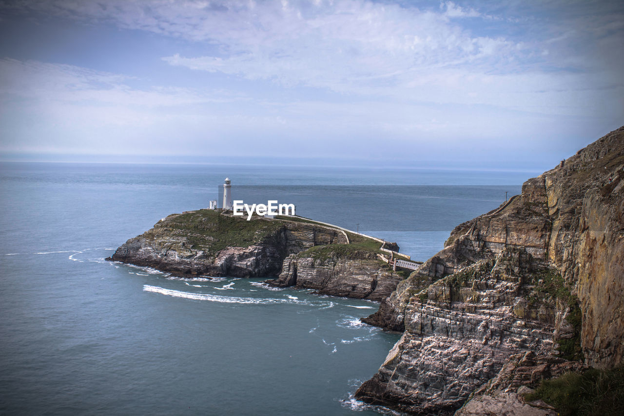 Scenic view of sea by cliff against sky