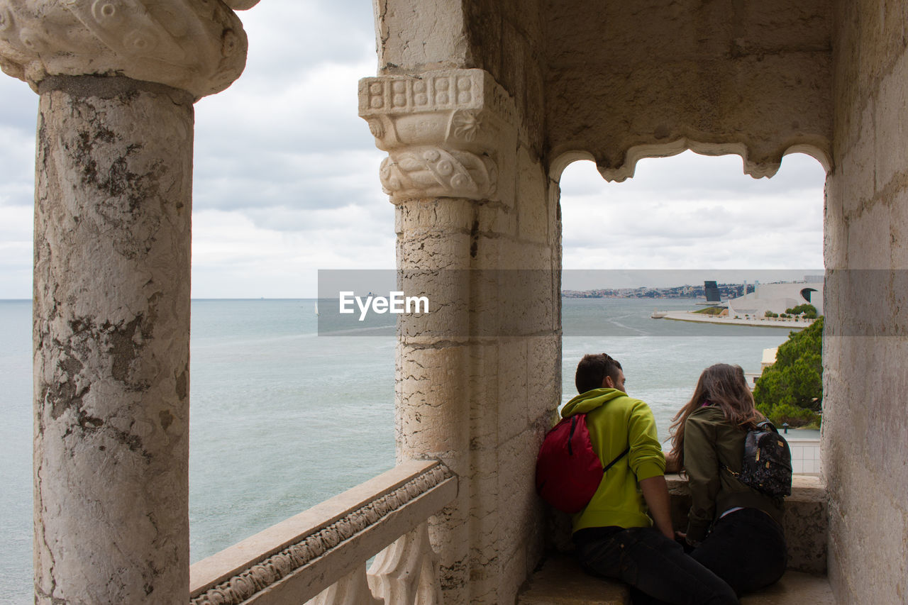 REAR VIEW OF PEOPLE LOOKING AT SEA VIEW