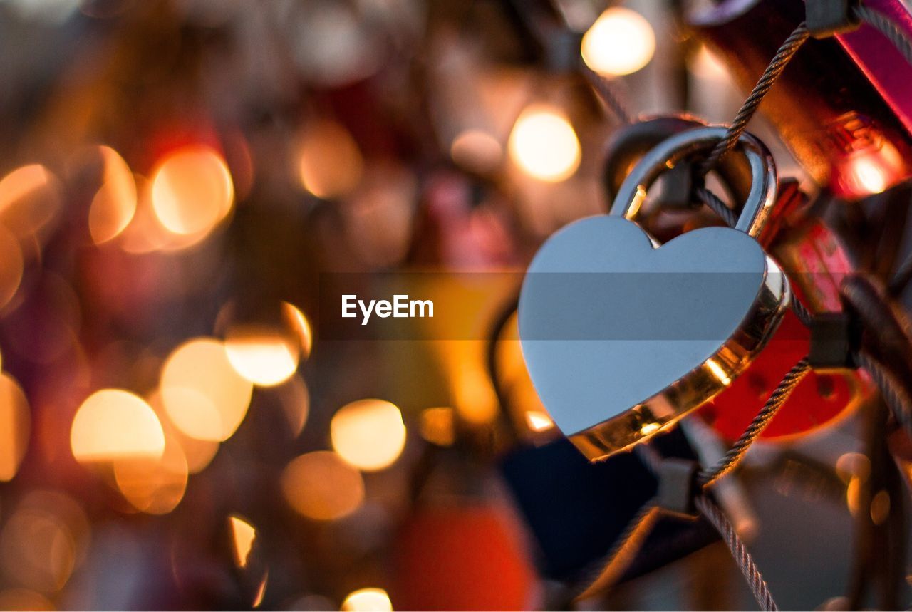 Close-up of heart shape love lock on railing during christmas at night