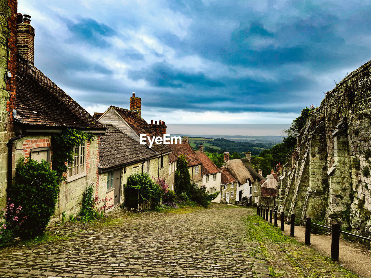 HOUSES BY BUILDINGS AGAINST SKY