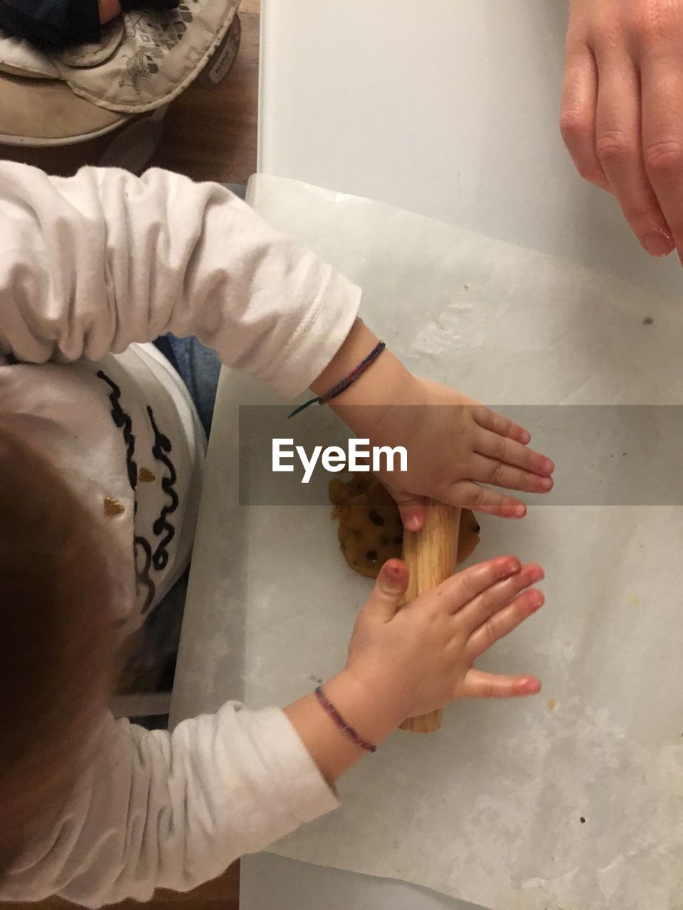 HIGH ANGLE VIEW OF HANDS HOLDING BABY AT HOME