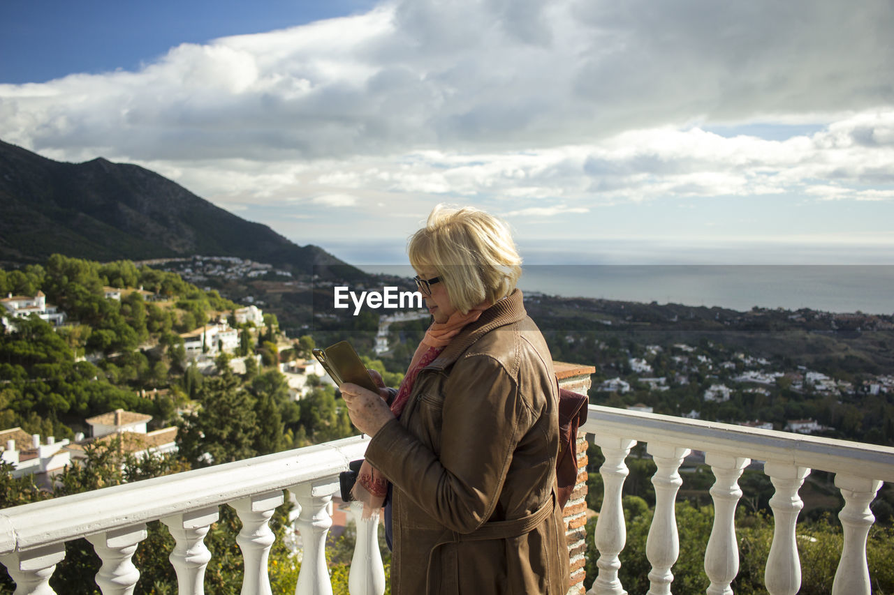 Woman using mobile phone against sky