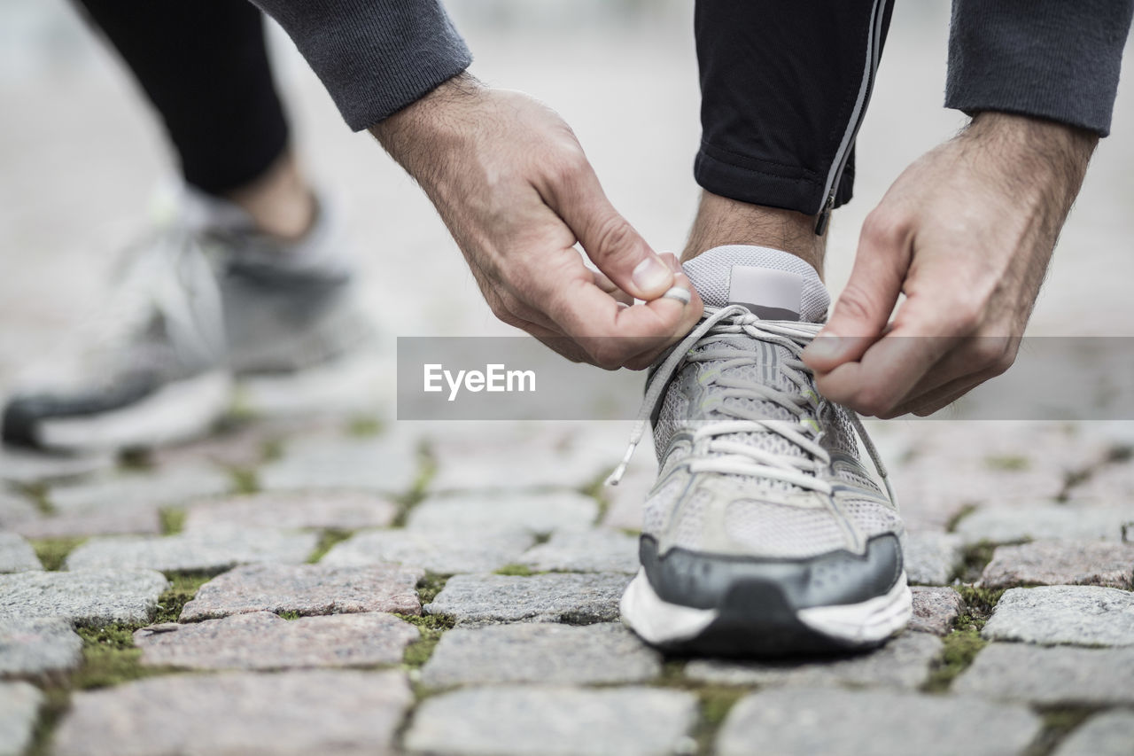 Low section of man tying lace of sports shoe