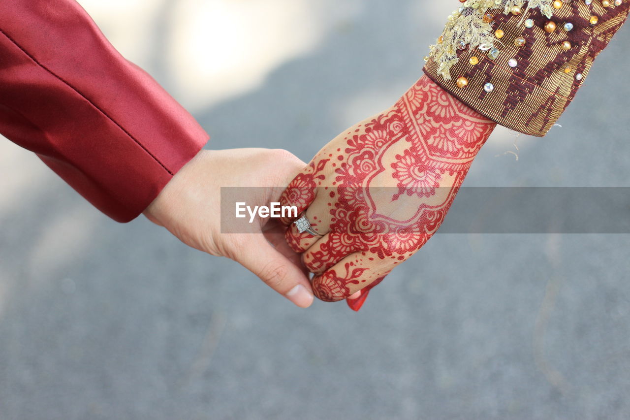 Cropped hand of groom holding bride hand