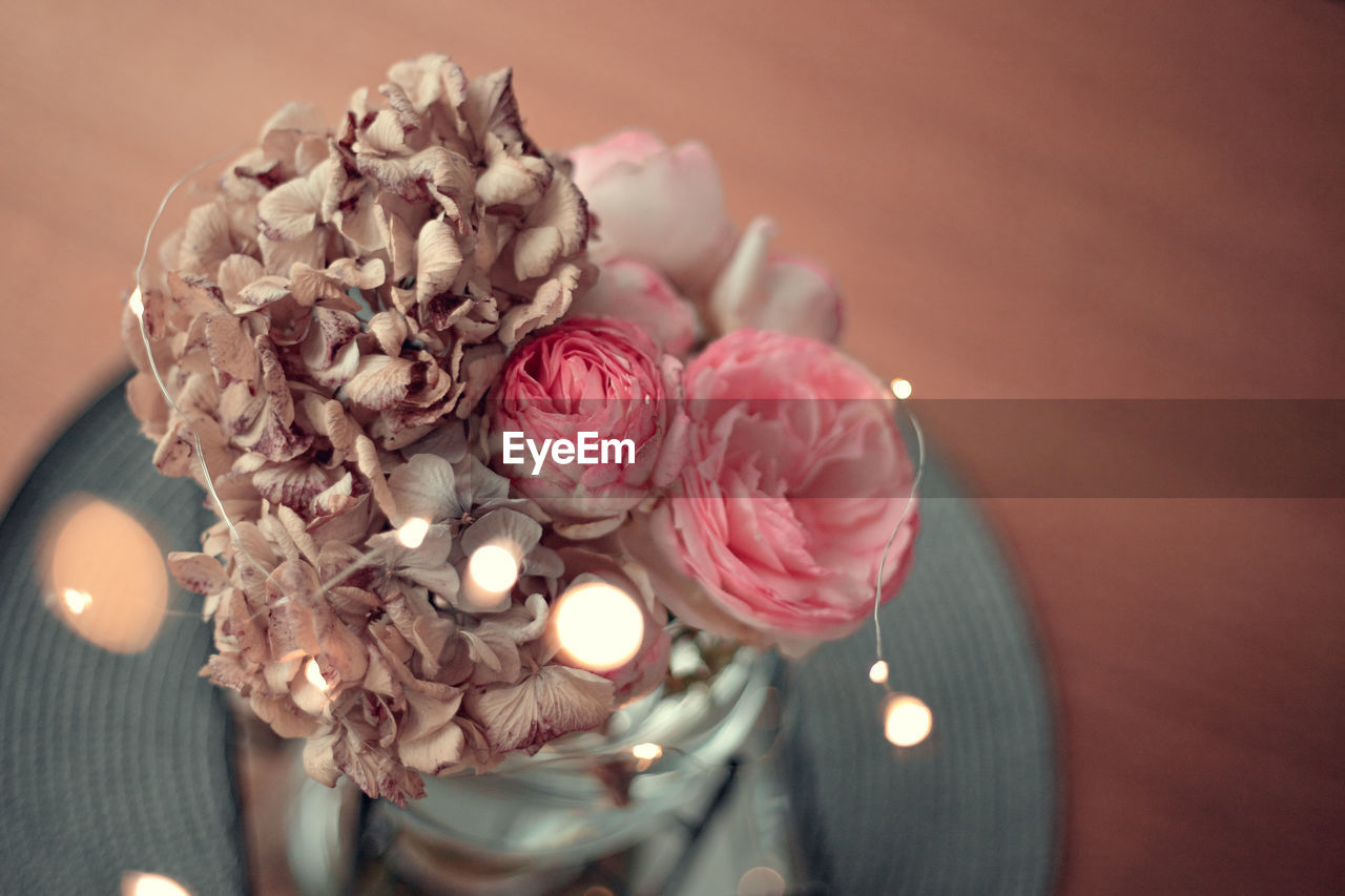 HIGH ANGLE VIEW OF ROSE FLOWER BOUQUET ON ILLUMINATED TABLE