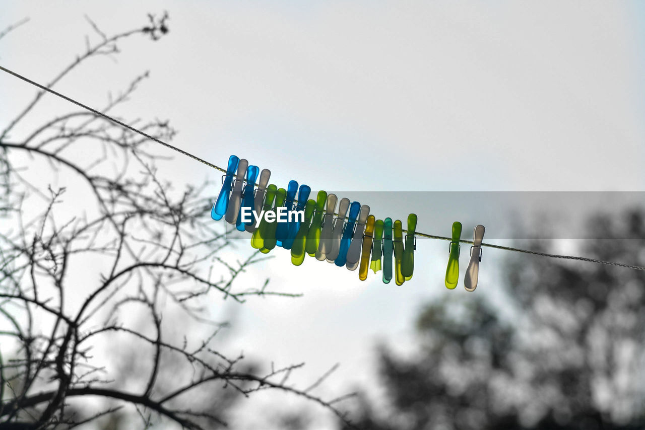 Low angle view of pegs hanging on clothesline against sky